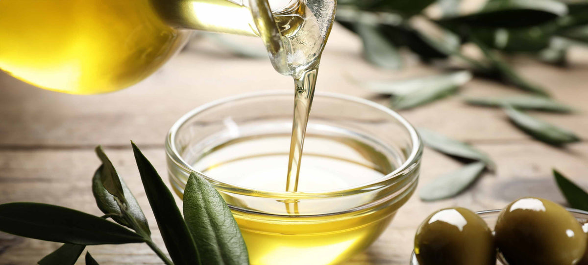 RENOWNED FOR ITS QUALITY AND TASTE: WHAT IS AWARD-WINNING OLIVE OIL? Fresh olive oil poured into a bowl with olives and leaves.