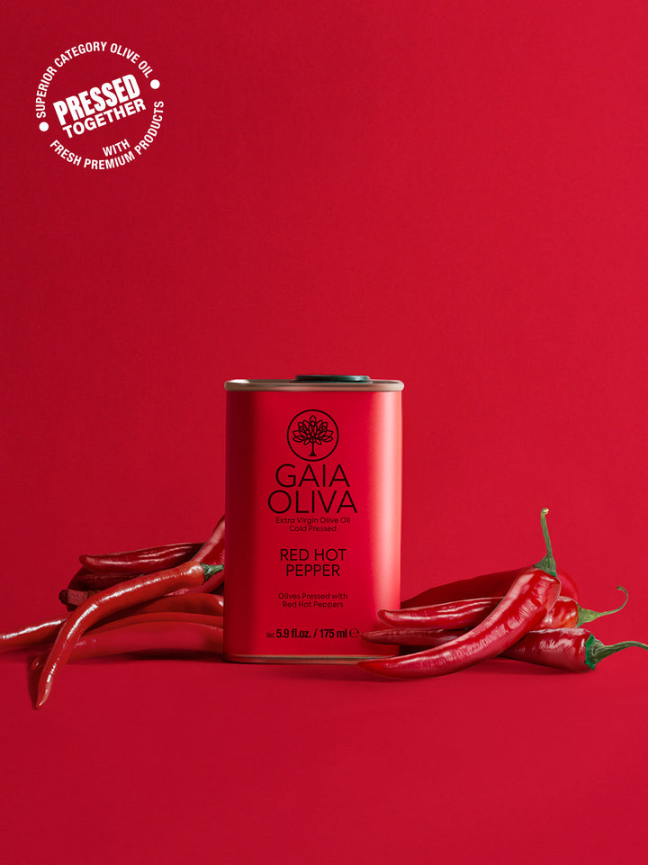 a tin of red hot pepper extra virgin olive oil with fresh peppers, red background