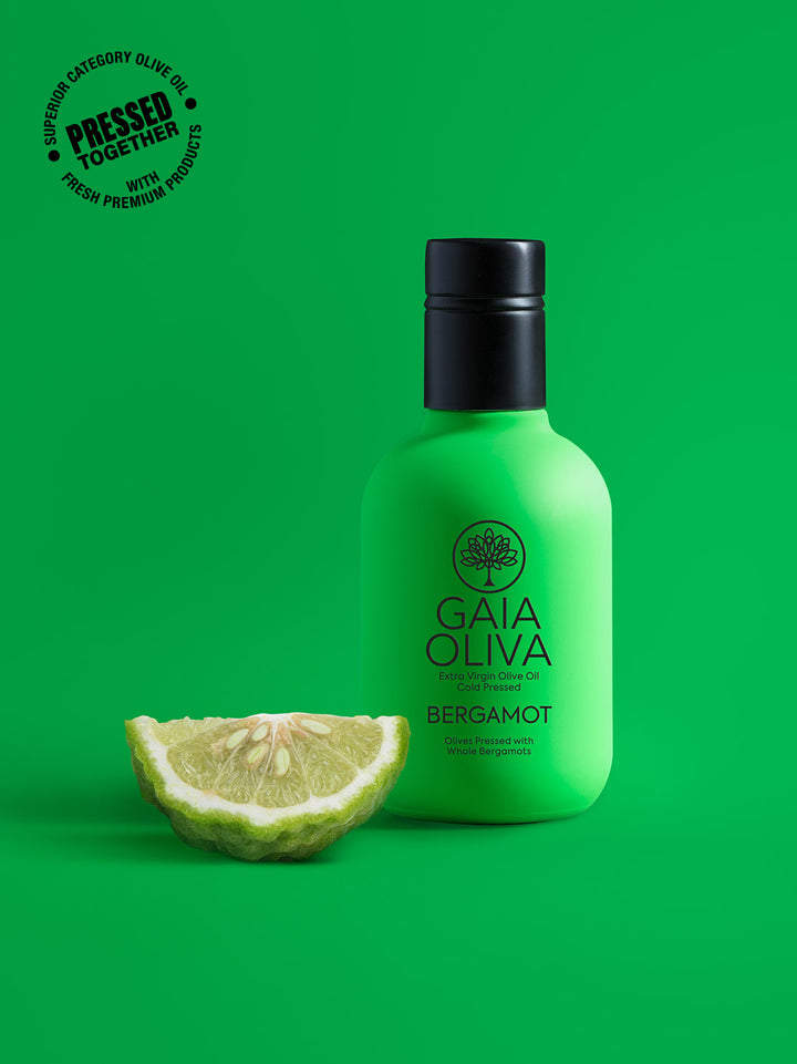a bottle of Bergamot Extra Virgin Olive Oil with fresh bergamot , green background