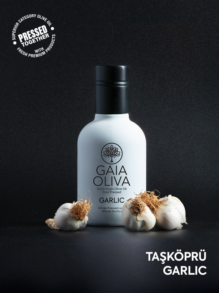 Bottle of Gaia Oliva Garlic Extra Virgin Olive Oil with fresh garlic cloves , black color background