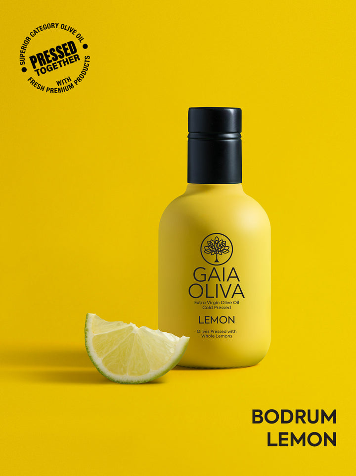 a bottle of Gaia Oliva Lemon Extra Virgin Olive Oil with fresh lemon, yellow background