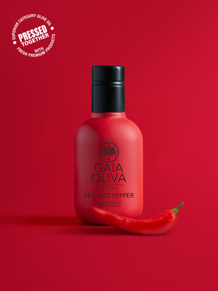 a bottle of Red Hot Pepper Extra Virgin Olive Oil with fresh pepper, red background