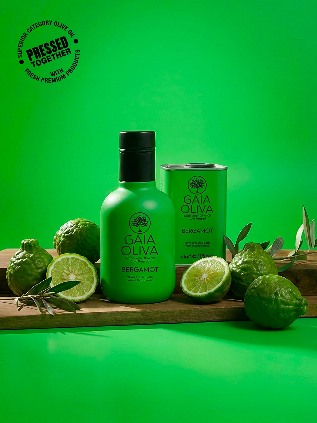 a bottle of Bergamot Extra Virgin Olive Oil with fresh bergamot ans small tin on wooden surface , green background