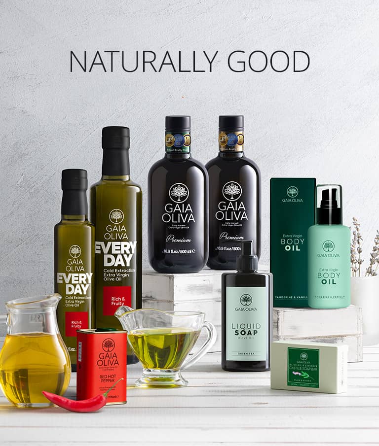 A collection of Gaia Oliva natural body care products arranged on white blocks against a light gray textured background, with the text 'NATURALLY GOOD' at the top. The products include olive oil bottles, a liquid soap bottle, a body oil bottle, a soap bar, a red body butter tube, and a glass of oil.