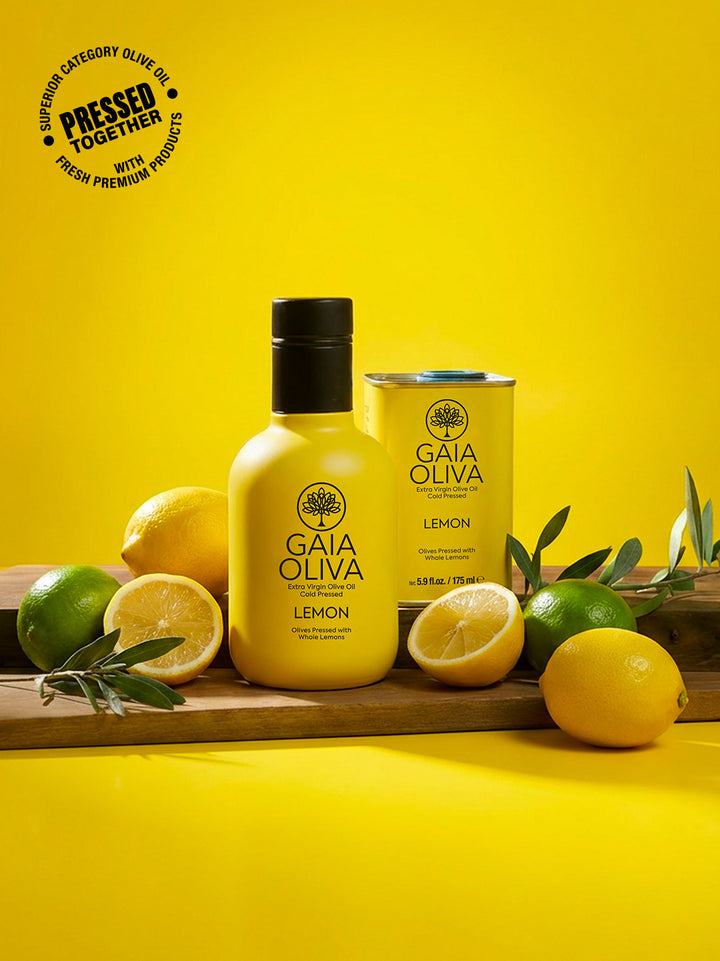 a bottle of Gaia Oliva Lemon Extra Virgin Olive Oil with fresh lemon and small tin on wooden surface, yellow background