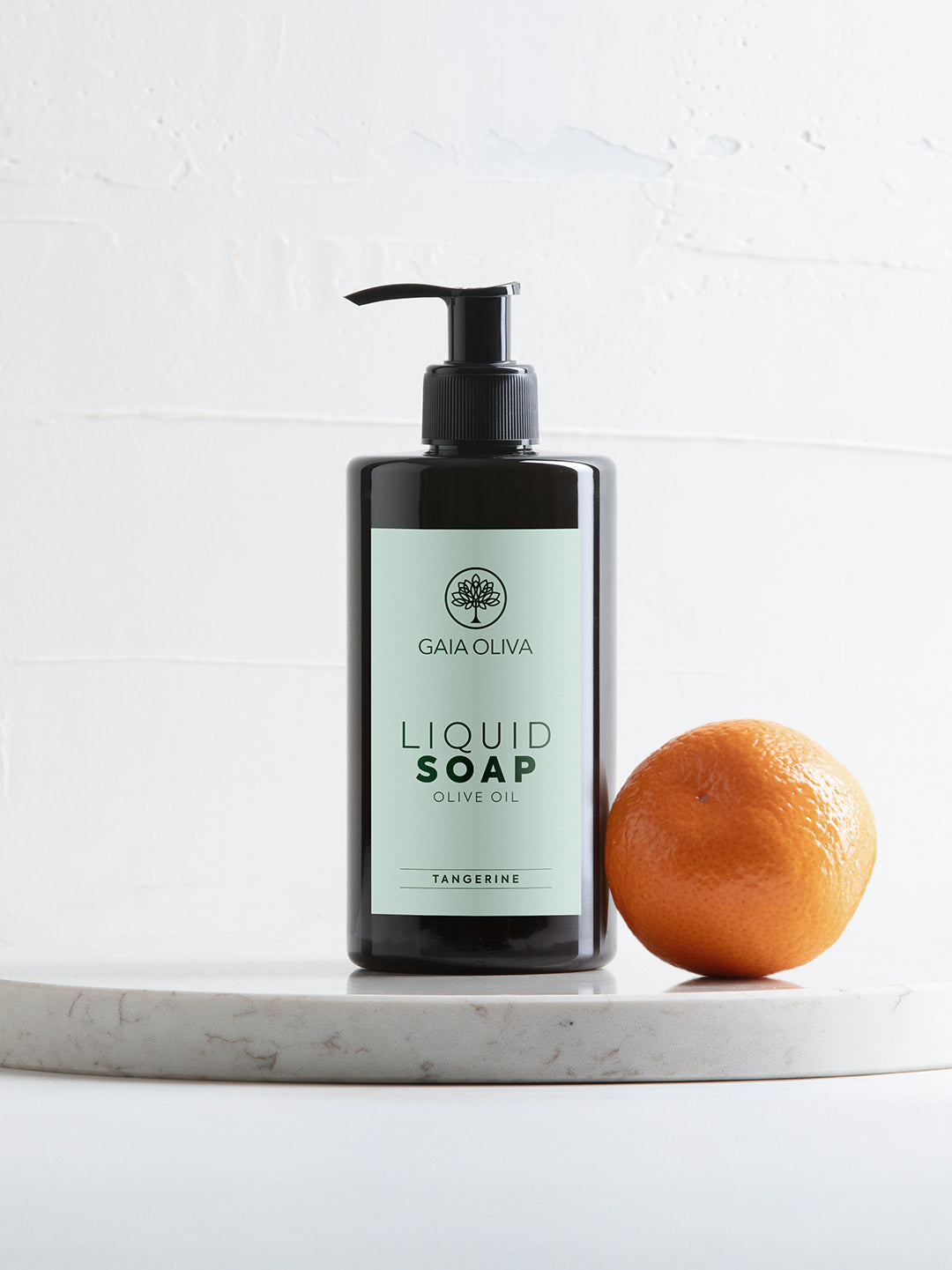 Olive Oil Liquid Soap with Tangerine on a white surface with whole tangerine fruit