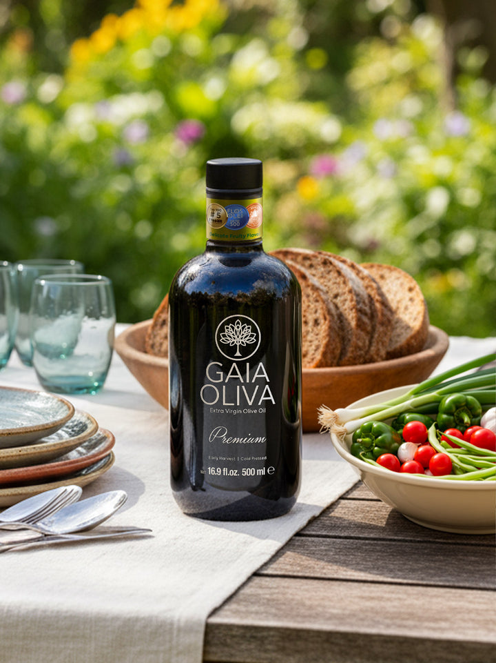 Premium Yamalak Early Harvest Extra Virgin Olive Oil bottle on a dining table with bread and fresh vegetables.